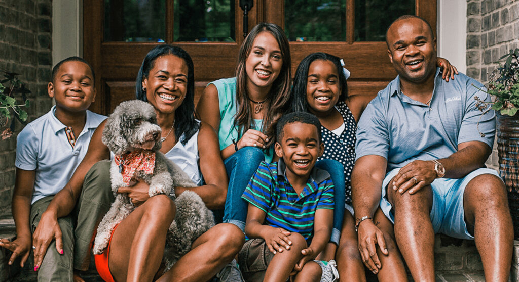african american family poses with three kids, a dog, and the family's visiting au pair